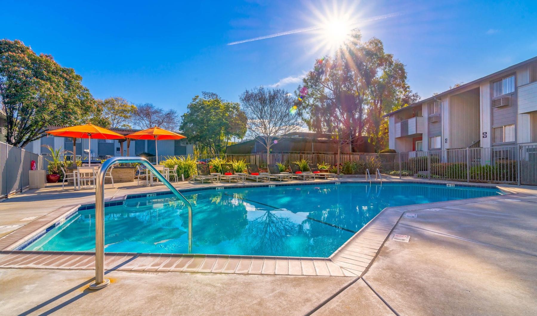 a swimming pool with chairs and umbrellas